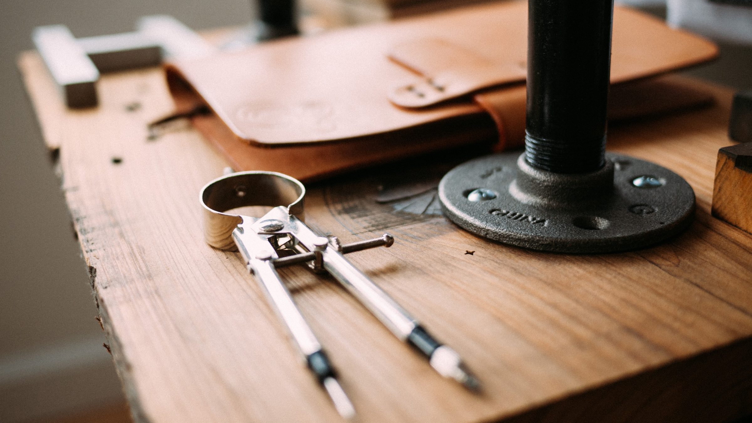 Our Process page banner image. Wooden work table with leather bound notebook and tools