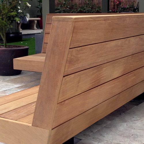 View from the back and side of unstained L-shaped wooden bench