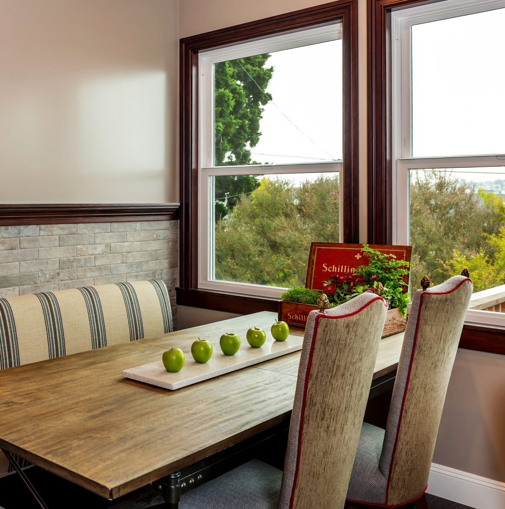 Kitchen table perpendicular to dark wood molding around kitchen windows and along wall