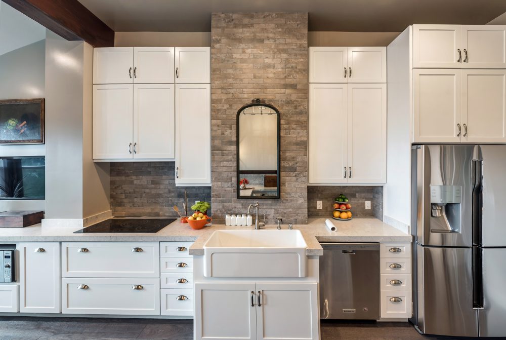 Standing in front of the farmhouse sink with electric stovetop to the left and countertop to the right. Lots of storage behind white cabinets