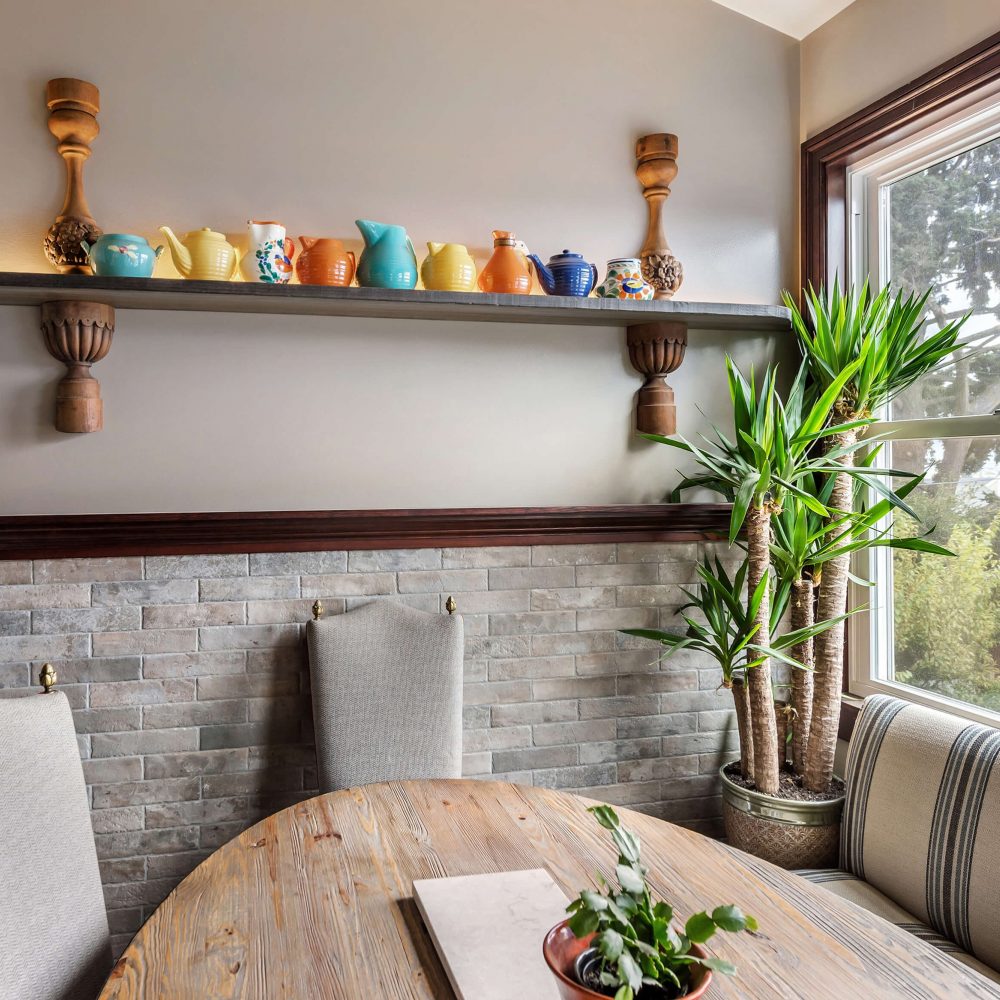 Kitchen table with built-in seating under window, one shelf with ceramic pitchers