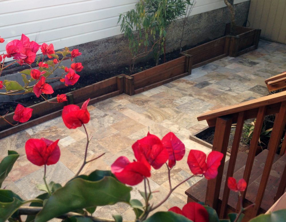 Bottom of steps leading down to a various beige-colored stone patio