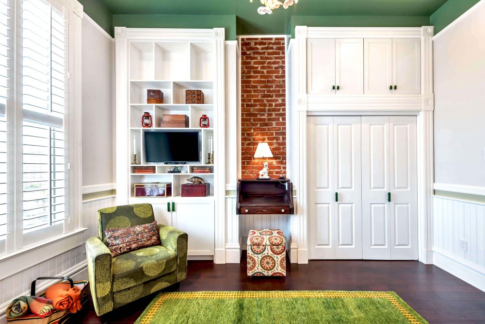 Straight view of Fair Oaks entertainment center and desk built-in's with green comfy chair, green rug, and white closet doors