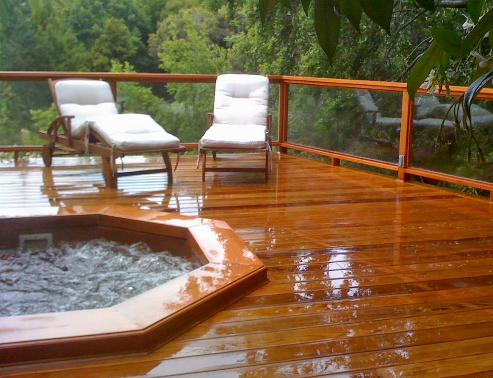 Large redwood deck around sunken hot tub with two cushioned lounge chairs