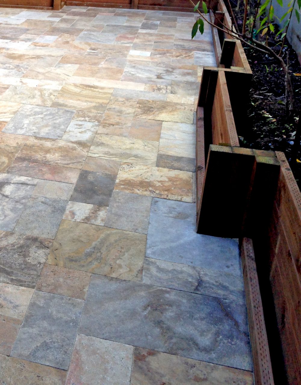 Beige and grey toned patio stones fit perfectly together for a smooth surface wrapping perfectly around a built-in planter box