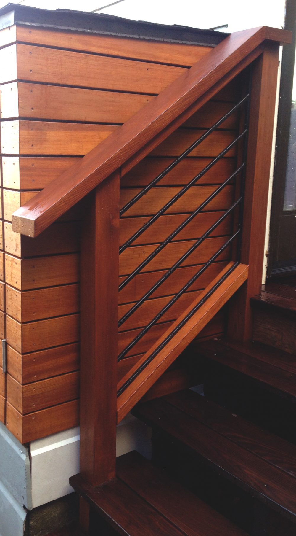 Dark stained wooden hand rail with black cable slats